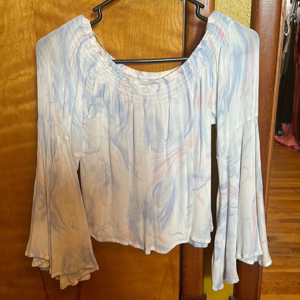 An off the shoulder flowy white shirt with pink and blue swirls